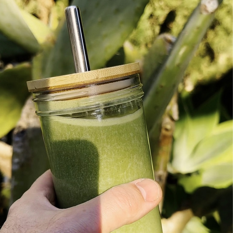 A hand holding a green smoothie made with Nutrilite Organics Plant Protein.