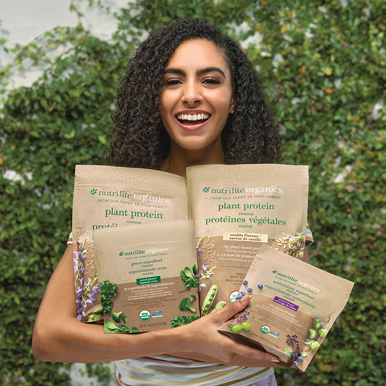 Woman holding Nutrilite Organics Plant Protein Powder, Green Superfood Powder, and Antioxidant Superfood Powder
