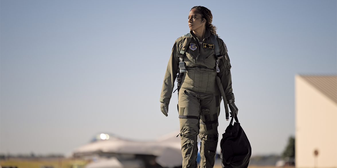 Rochelle Kimbrell walks down an tarmac with a fighter plane in the background.